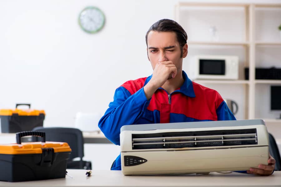 Young Repairman Repairing Air-Conditioner At Warranty Center