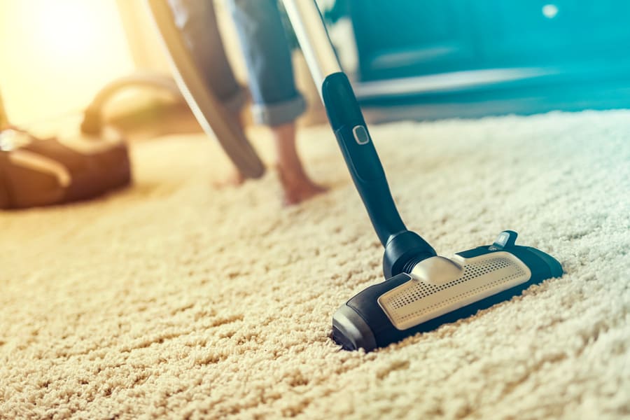 Young Woman Using A Vacuum Cleaner While Cleaning Carpet In The House
